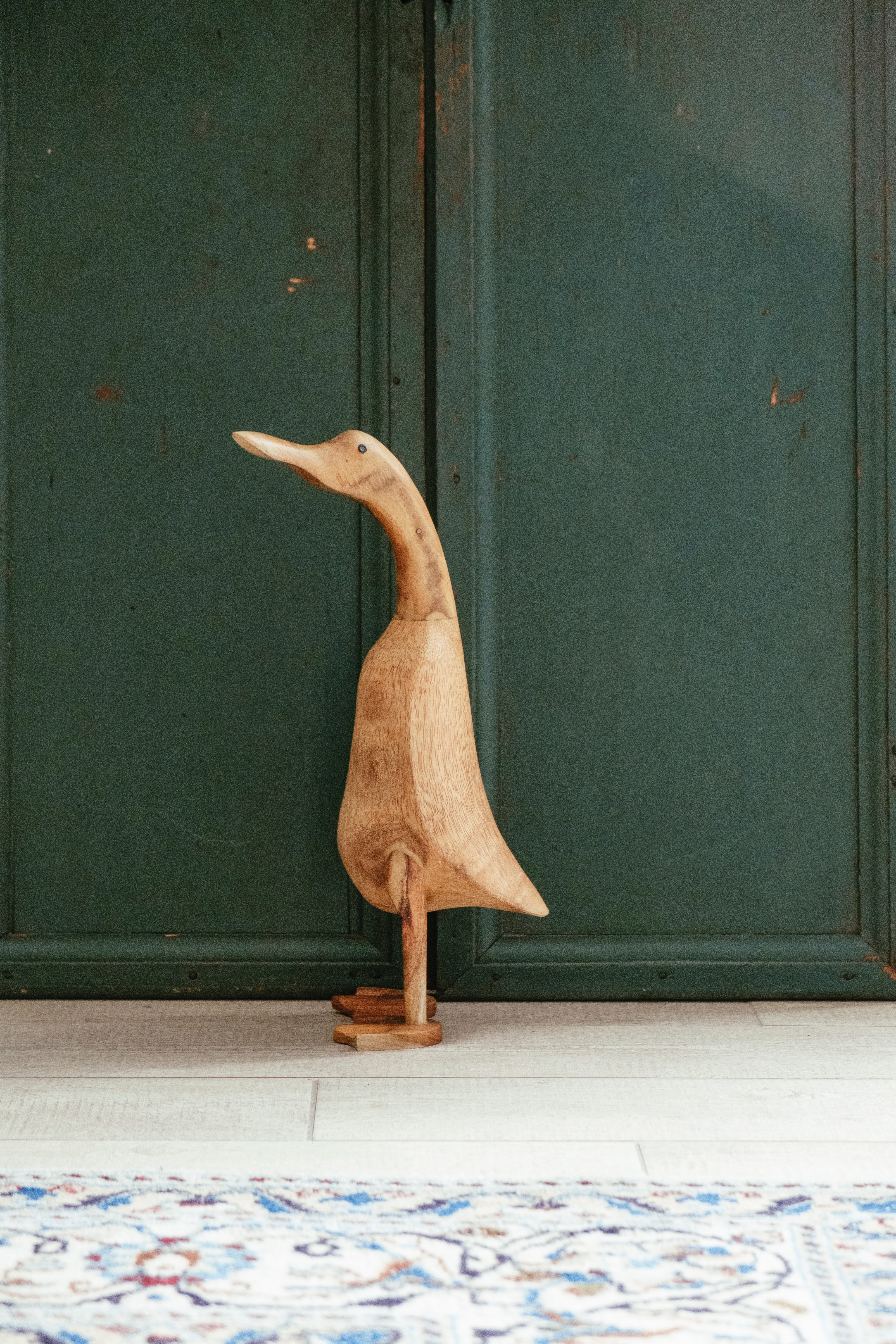 Image of a wooden duck sculpture with a green background.